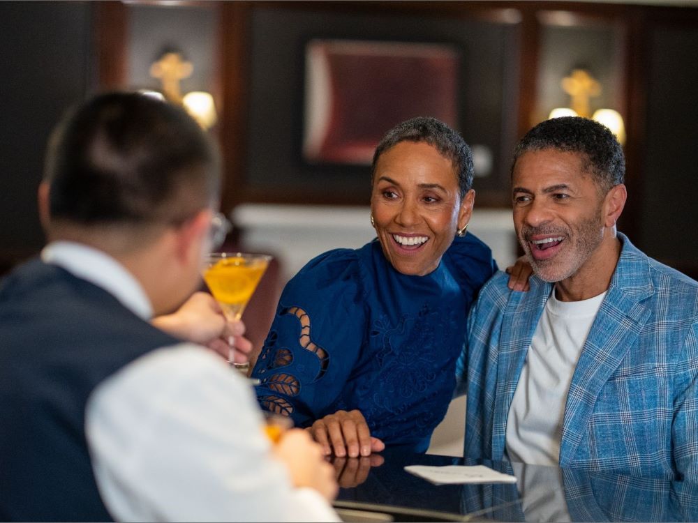 couple at bar with bartender passing a drink over
