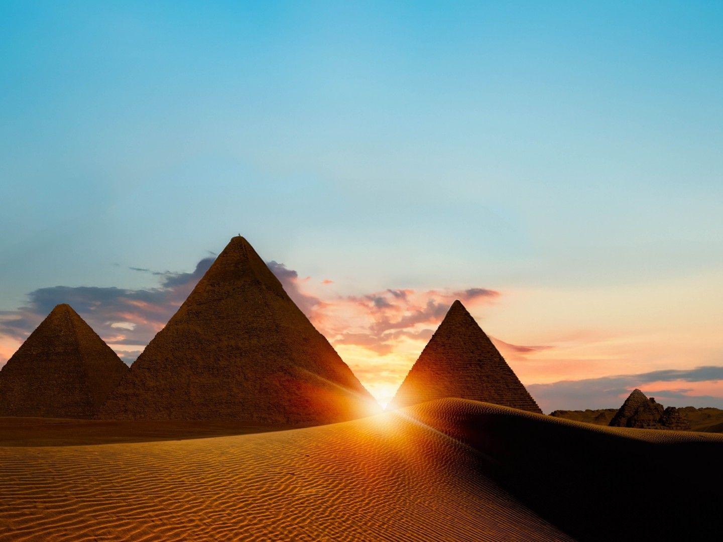 sunrise peeking though pyramids in desert shadows